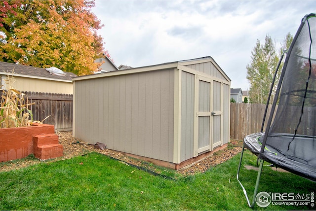 view of outbuilding featuring a lawn and a trampoline