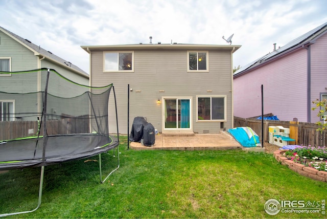 rear view of property with a patio area, a lawn, and a trampoline