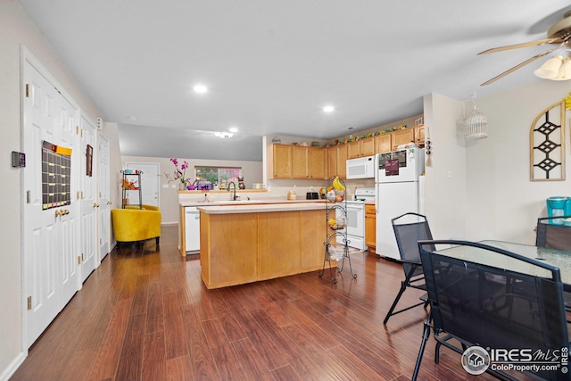 kitchen featuring dark wood-type flooring, sink, a center island, a breakfast bar, and white appliances