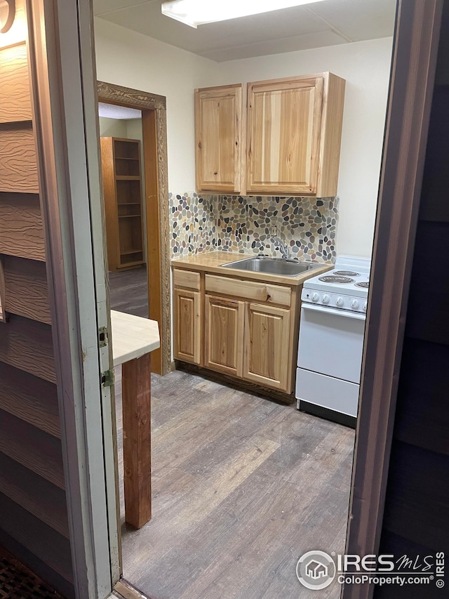 kitchen featuring light brown cabinets, sink, light wood-type flooring, stove, and tasteful backsplash