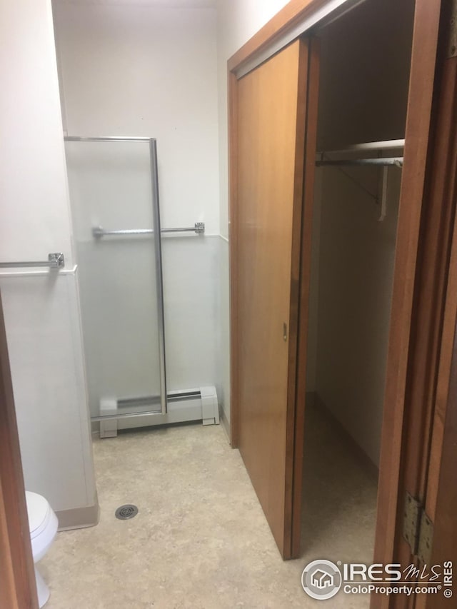 bathroom featuring baseboard heating, concrete flooring, and toilet