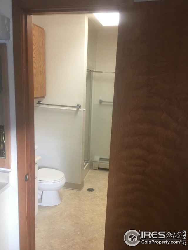 bathroom with a baseboard radiator, toilet, and a shower with shower door