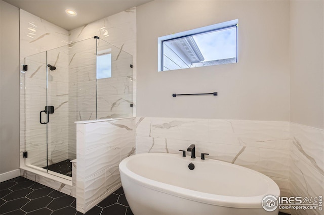 bathroom with tile patterned floors, tile walls, and shower with separate bathtub