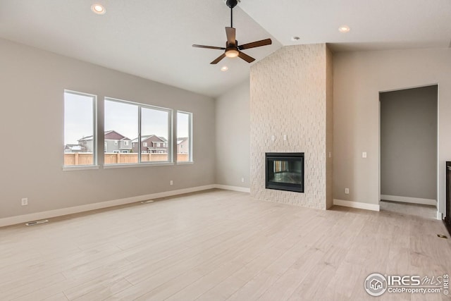 unfurnished living room with a large fireplace, light hardwood / wood-style floors, vaulted ceiling, and ceiling fan