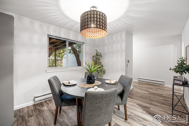 dining area with hardwood / wood-style floors, baseboard heating, and a notable chandelier