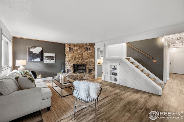 living room featuring wood-type flooring and a stone fireplace