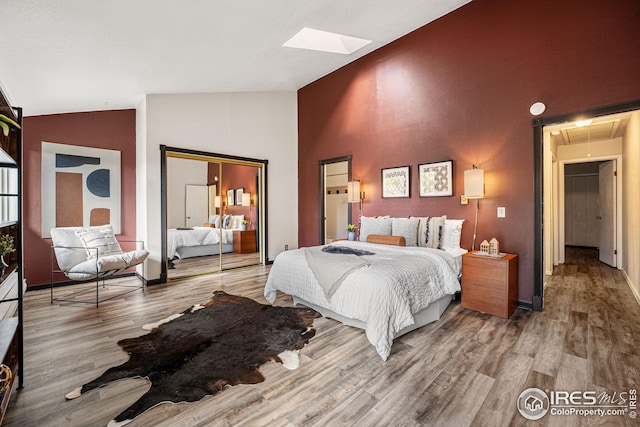 bedroom with hardwood / wood-style flooring and high vaulted ceiling