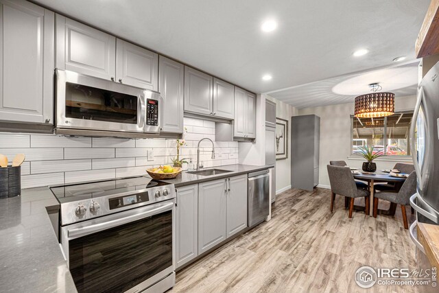 kitchen with appliances with stainless steel finishes, light hardwood / wood-style floors, and sink