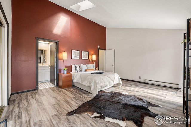 bedroom featuring ensuite bathroom, wood-type flooring, a skylight, high vaulted ceiling, and baseboard heating