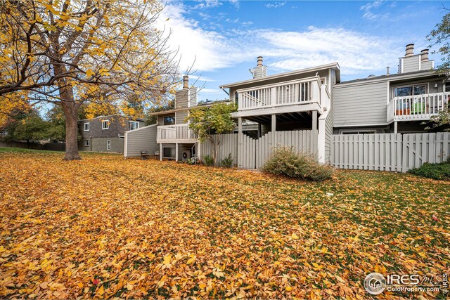 back of property featuring a balcony and a yard