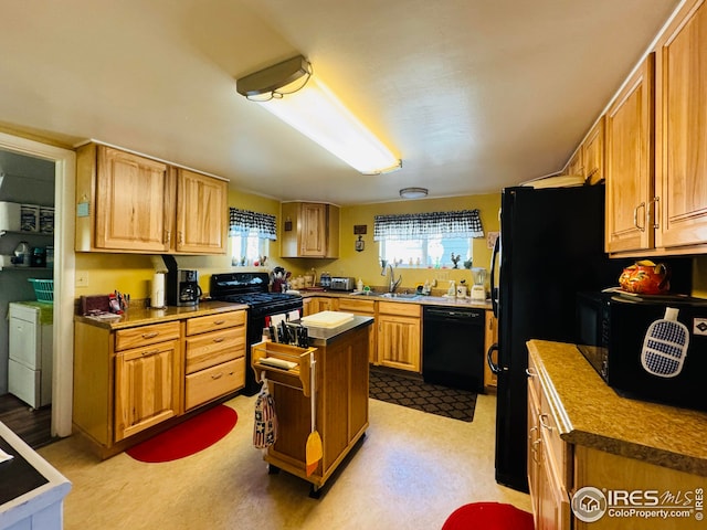 kitchen featuring black appliances, sink, washer and clothes dryer, and a kitchen island