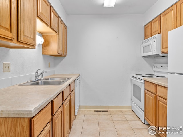 kitchen with light tile patterned floors, white appliances, and sink