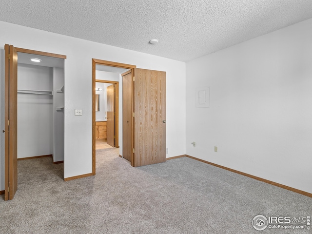 unfurnished bedroom featuring a textured ceiling, light carpet, and a closet