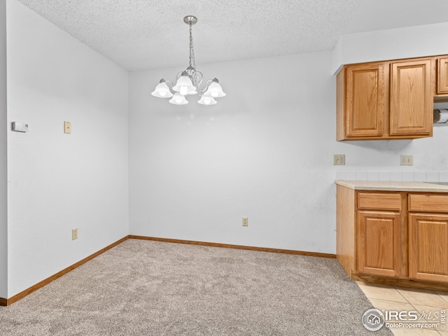 unfurnished dining area with a textured ceiling, light carpet, and a chandelier