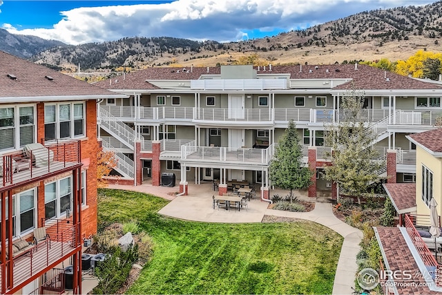 rear view of property with a patio area, a mountain view, and a yard