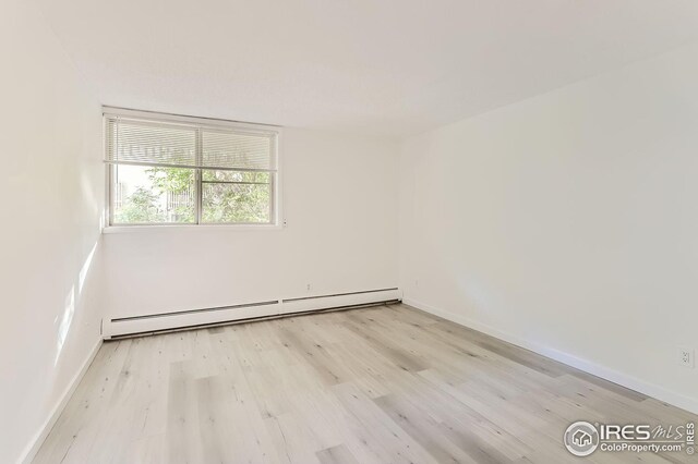 spare room with light hardwood / wood-style floors and a baseboard heating unit