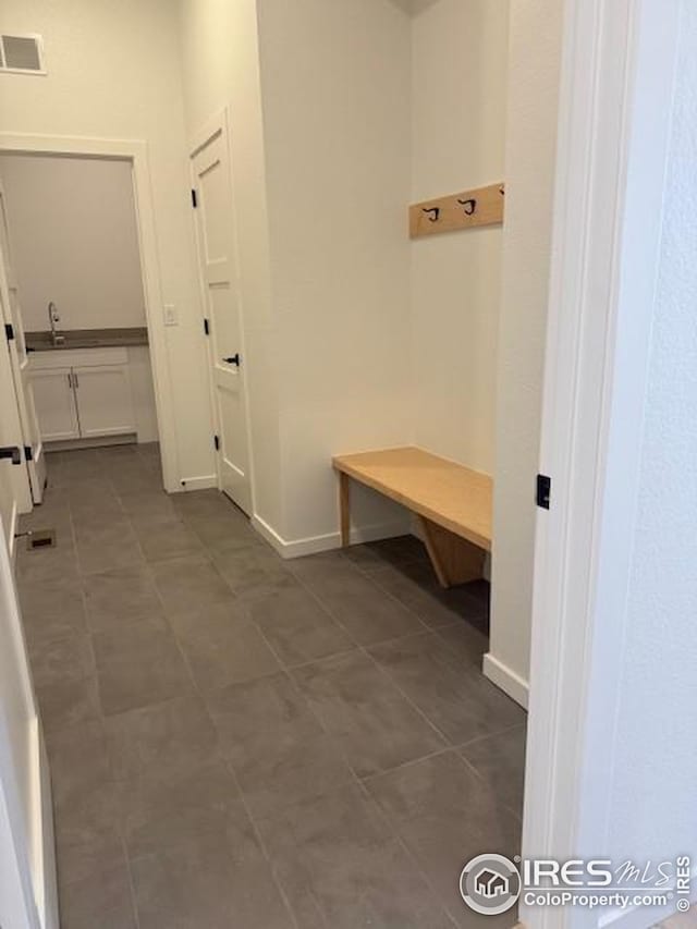 mudroom with tile patterned floors, a sink, visible vents, and baseboards