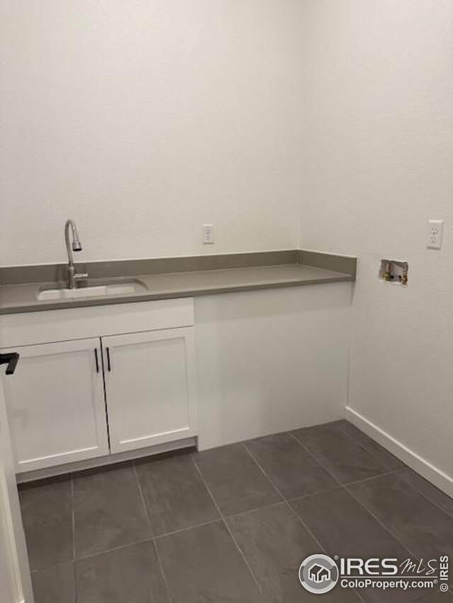 washroom with dark tile patterned flooring, washer hookup, cabinet space, and a sink