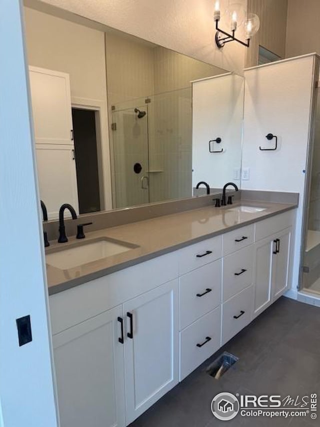 bathroom with double vanity, a sink, visible vents, and a shower stall