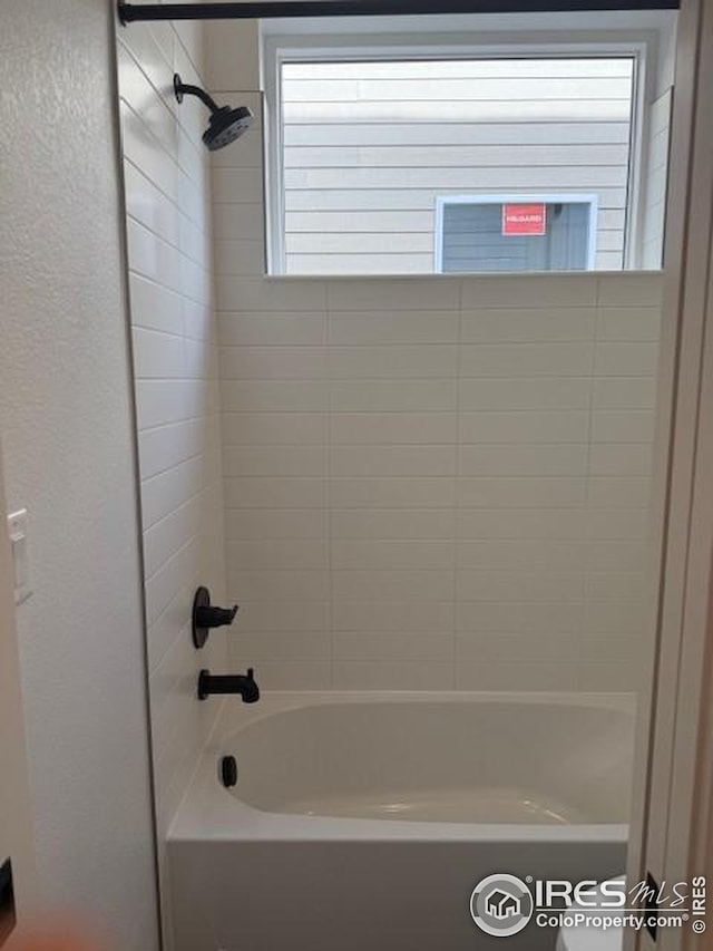 bathroom with bathtub / shower combination and a textured wall