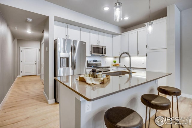 968 Birdwhistle Ln Unit 4, Fort Collins, CO 80524 - kitchen with light wood-style floors, appliances with stainless steel finishes, a kitchen bar, a sink, and baseboards
