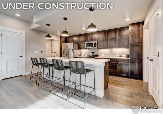 968 Birdwhistle Ln Unit 3, Fort Collins, CO 80524 - kitchen with decorative backsplash, appliances with stainless steel finishes, light countertops, dark brown cabinetry, and a kitchen island with sink