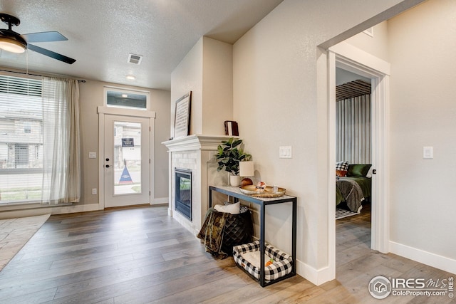 968 Birdwhistle Ln Unit 3, Fort Collins, CO 80524 - foyer with a fireplace, ceiling fan, a wealth of natural light, visible vents, and wood finished floors