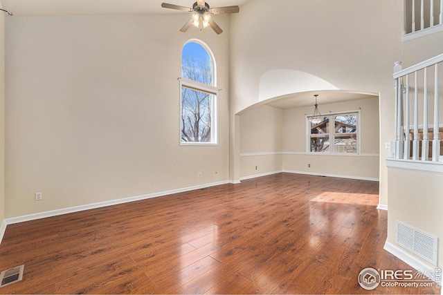 unfurnished room featuring arched walkways, visible vents, and hardwood / wood-style floors