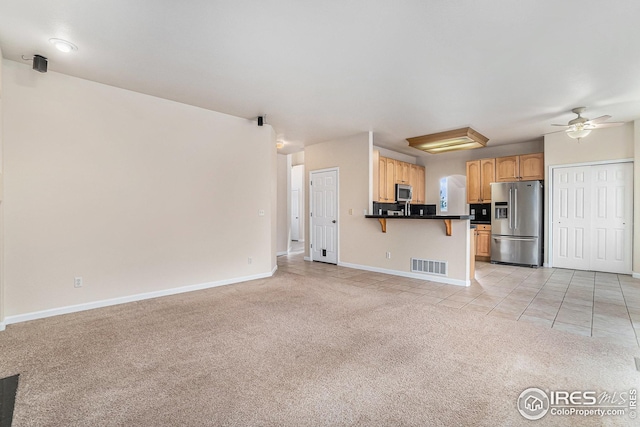 unfurnished living room featuring baseboards, visible vents, a ceiling fan, light colored carpet, and light tile patterned flooring