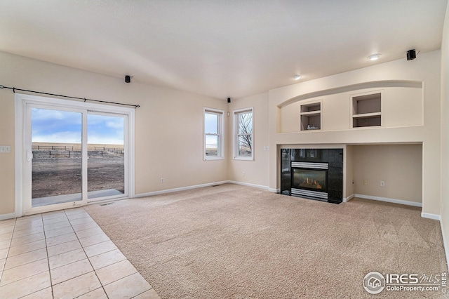 unfurnished living room featuring baseboards, light colored carpet, a tiled fireplace, and light tile patterned floors