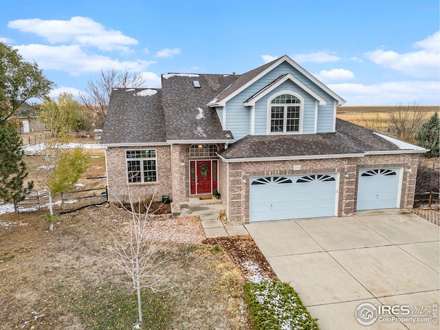 traditional home featuring brick siding, a shingled roof, concrete driveway, an attached garage, and fence