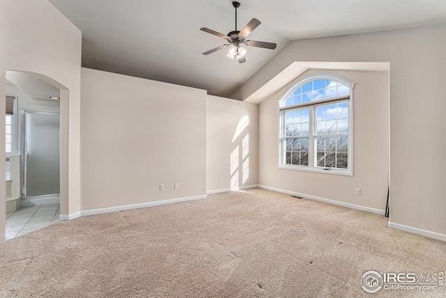 carpeted empty room featuring visible vents, arched walkways, baseboards, lofted ceiling, and ceiling fan