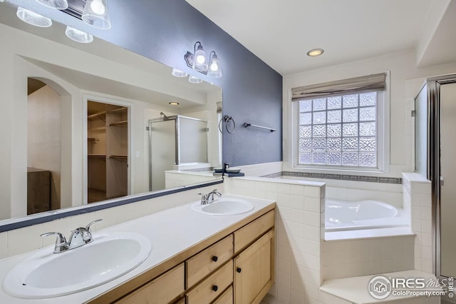 bathroom featuring double vanity, a stall shower, a sink, and a walk in closet