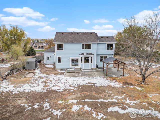rear view of house featuring roof with shingles, central AC unit, an outdoor structure, and a patio