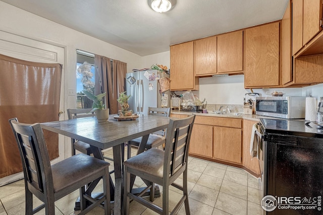 kitchen featuring light tile patterned flooring, refrigerator, sink, and electric range oven