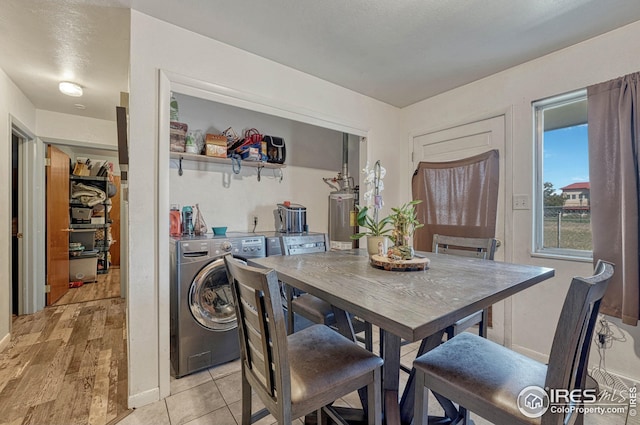 dining area featuring washer and clothes dryer, water heater, and light tile patterned flooring