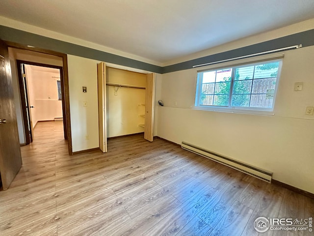 unfurnished bedroom with a closet, light hardwood / wood-style floors, and a baseboard radiator