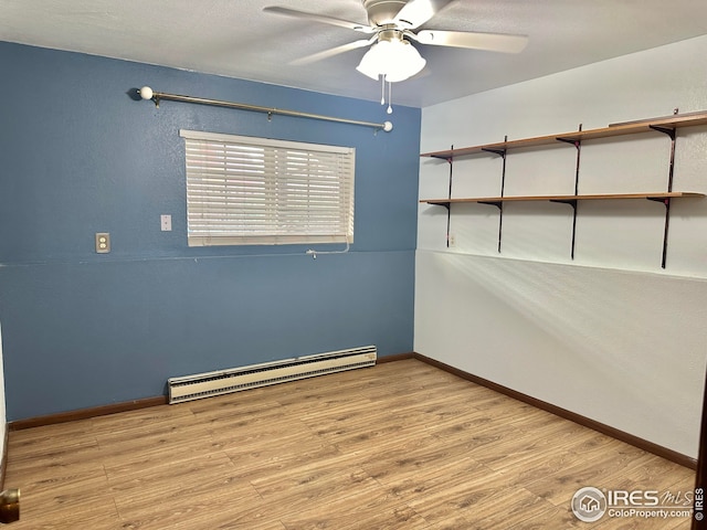 spare room featuring light hardwood / wood-style floors, a baseboard heating unit, and ceiling fan