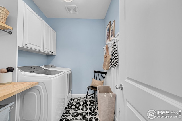 laundry room with cabinets, dark tile patterned floors, and washing machine and clothes dryer