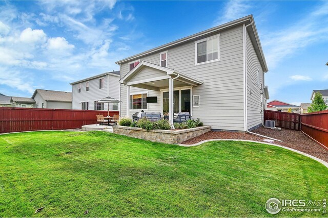 rear view of house with a yard, a patio, and central AC