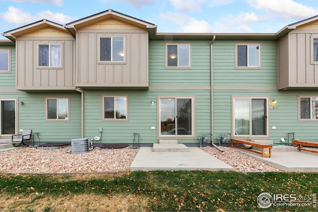 rear view of house with a patio, central AC unit, and board and batten siding
