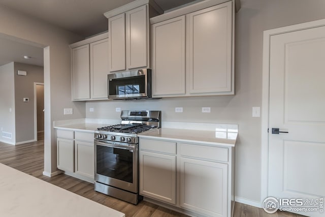 kitchen with wood-type flooring, white cabinets, and stainless steel appliances