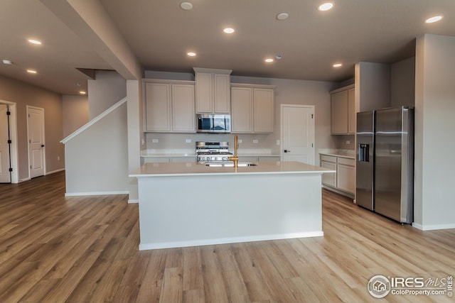 kitchen with a kitchen island with sink, sink, stainless steel appliances, and light hardwood / wood-style floors