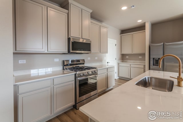 kitchen featuring dark hardwood / wood-style flooring, sink, light stone counters, and stainless steel appliances