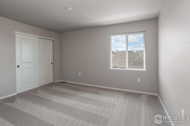 unfurnished bedroom featuring light colored carpet and a closet