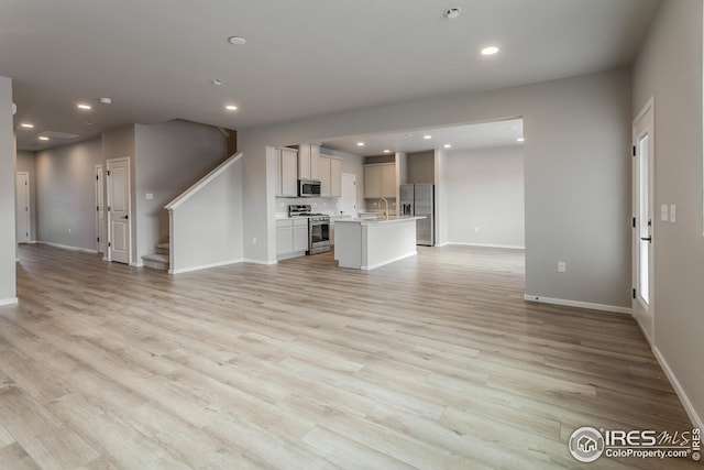 unfurnished living room featuring light hardwood / wood-style floors and sink