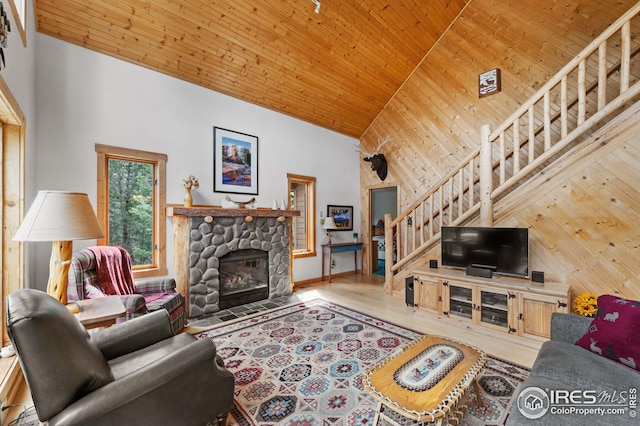 living area featuring stairs, high vaulted ceiling, wood ceiling, a stone fireplace, and wood finished floors