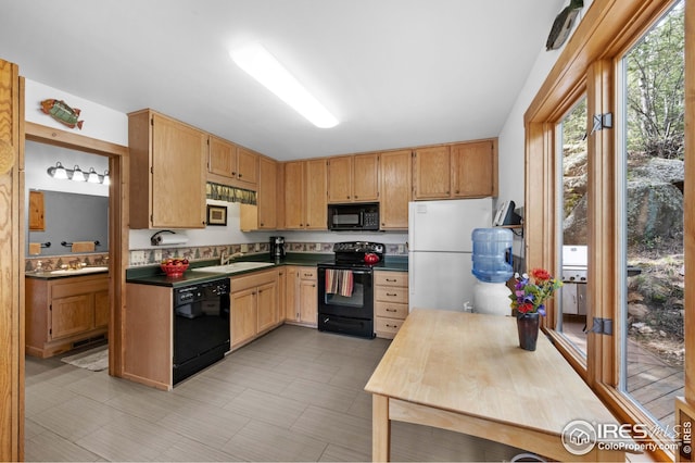 kitchen featuring dark countertops, black appliances, and a sink