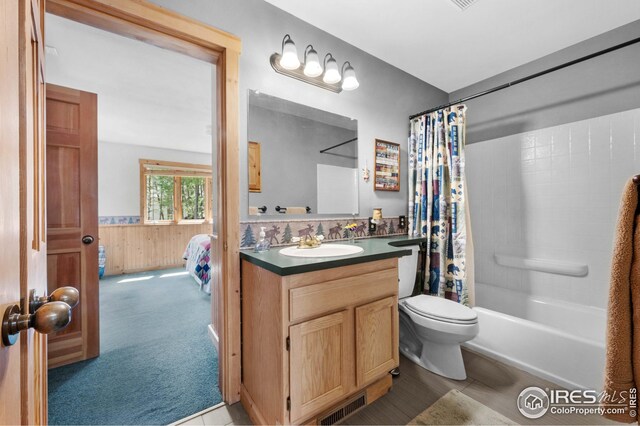bathroom with a wainscoted wall, toilet, vanity, wood walls, and visible vents