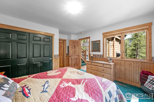carpeted bedroom with a closet, wood walls, and wainscoting